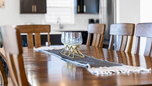 A dining table with a glass centerpiece, wooden chairs, and a dark rug.