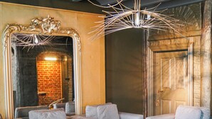 Un espacio lounge moderno con una mesa redonda para café, dos sofás y un espejo decorativo.