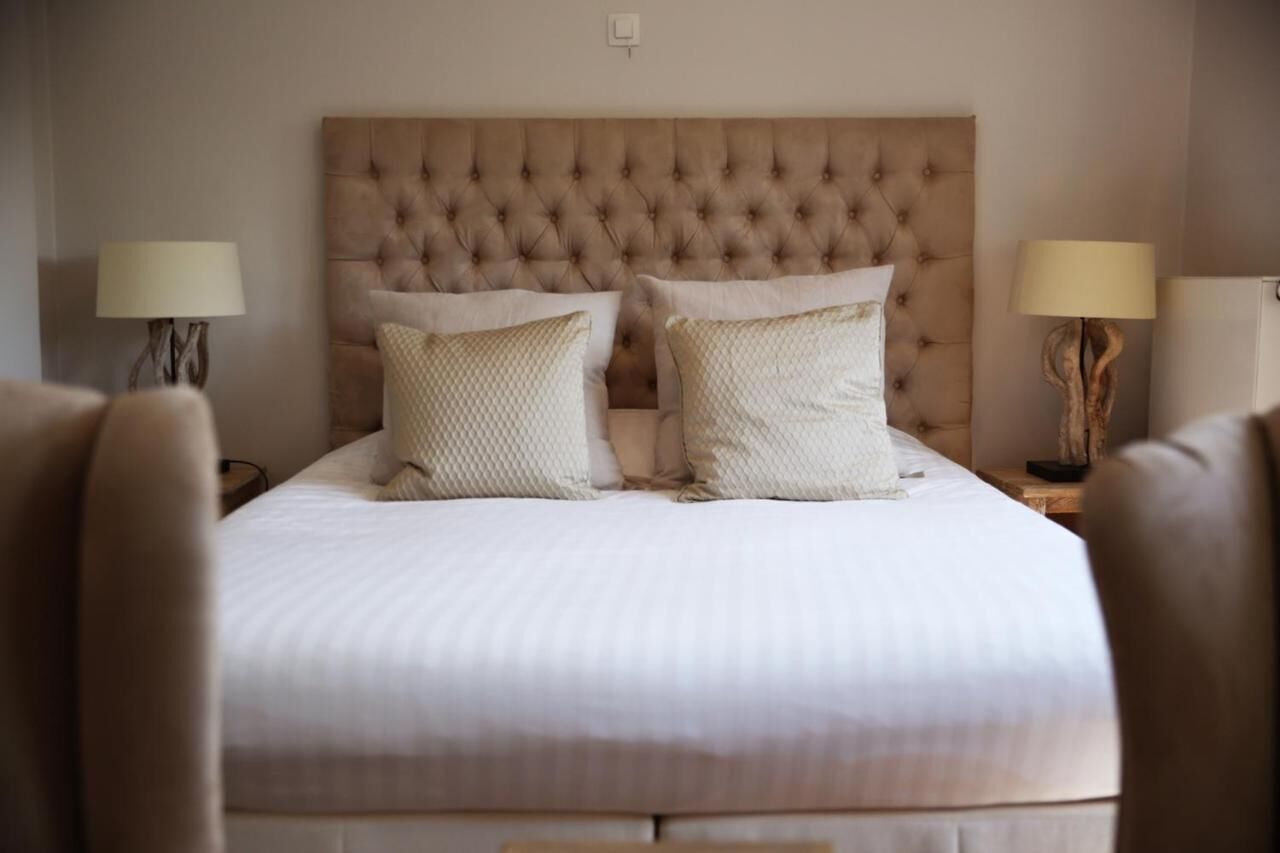 A neatly made bed with a tufted headboard, two bedside lamps, and a wooden nightstand.