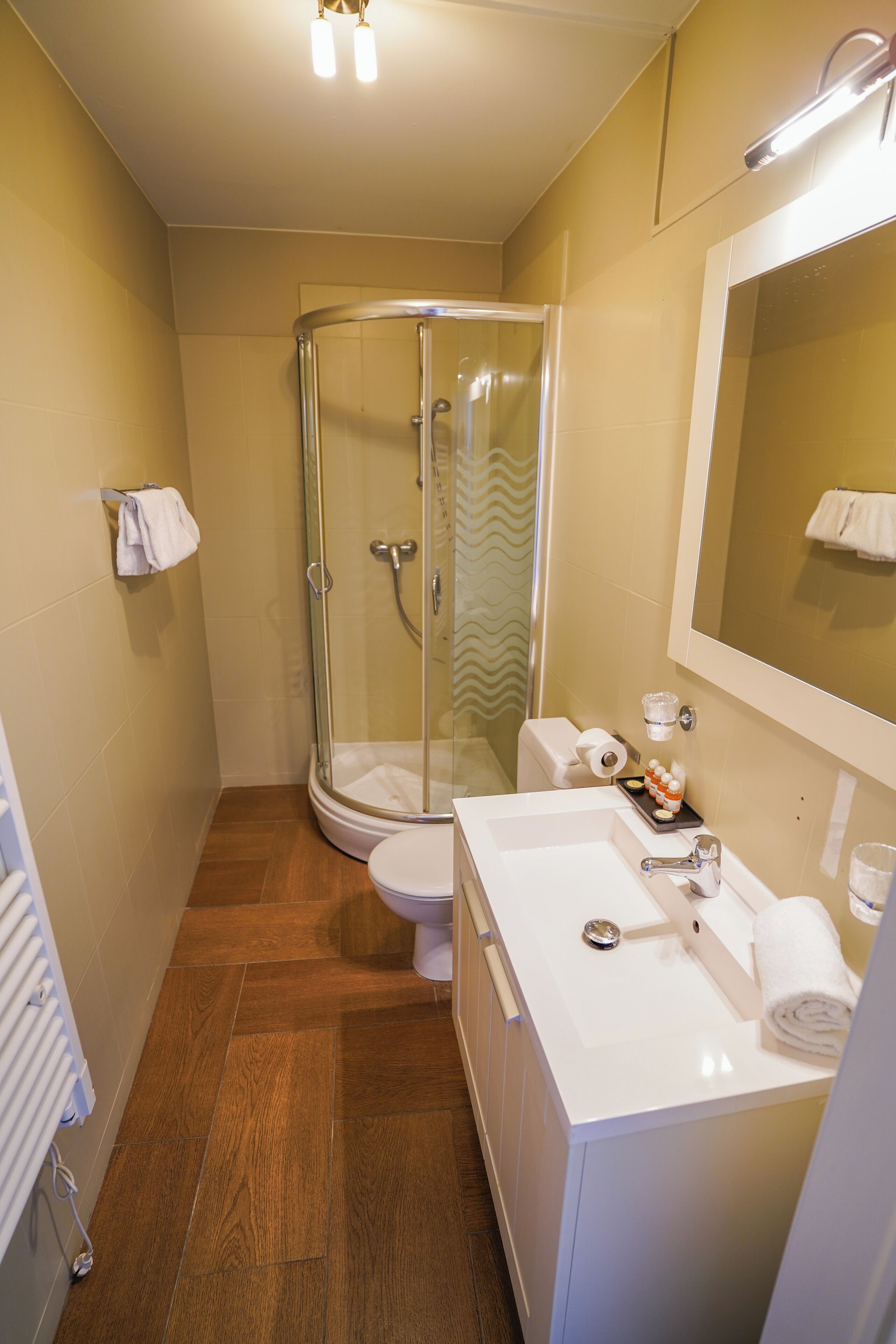Un baño con ducha de vidrio, lavamanos blanco y retrete.