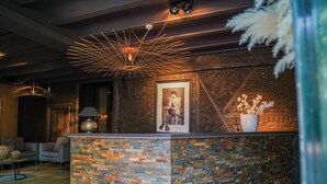 Un área de recepción con pared de ladrillo, una fotografía enmarcada y una lámpara colgante moderna.