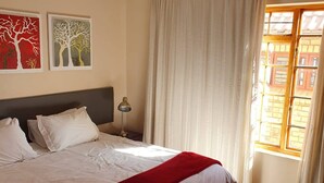 Une chambre à coucher avec un grand lit, une table de chevet, une lampe et deux œuvres d’art murales.