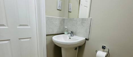 A bathroom with a toilet, sink, and mirror.