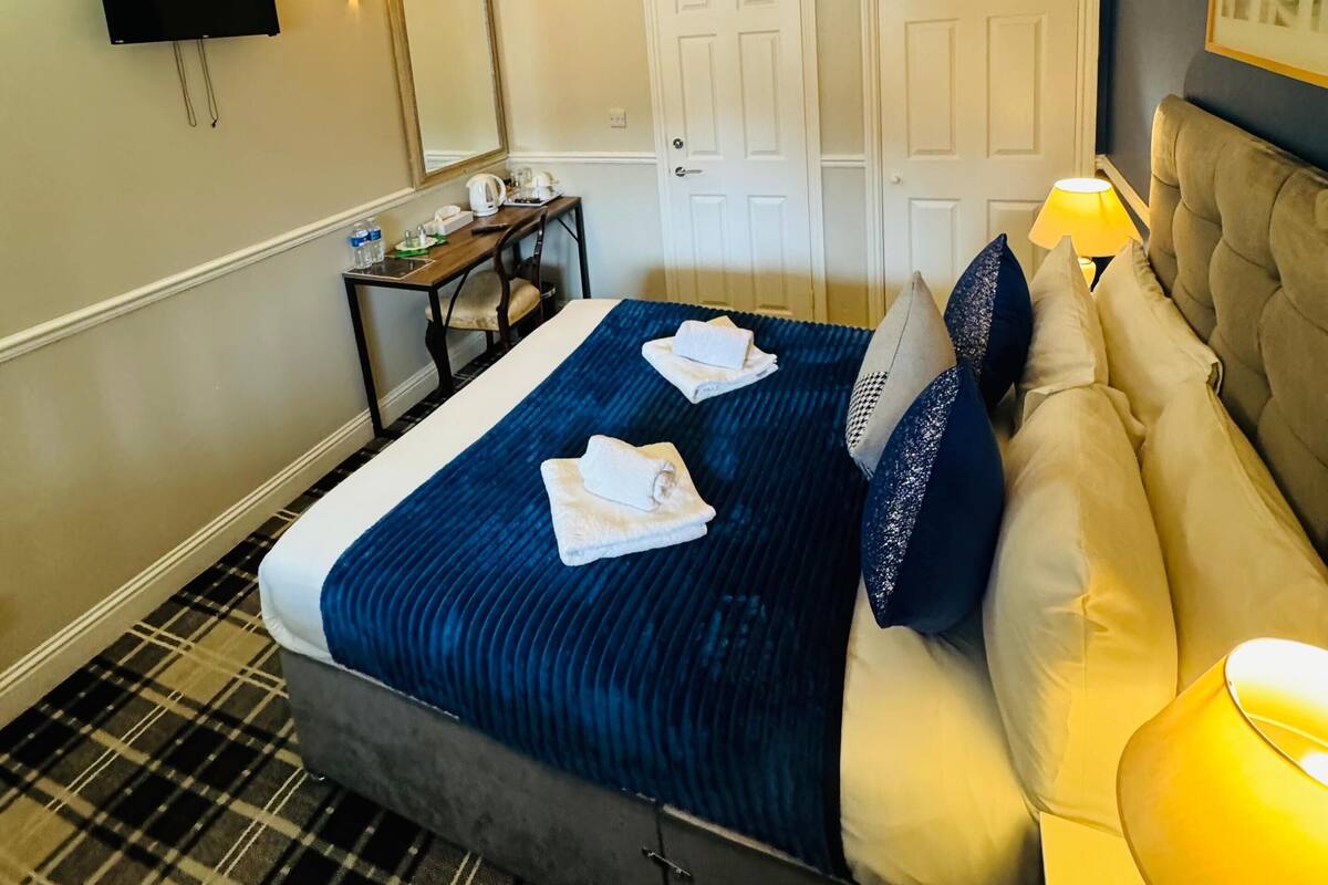Una habitación de hotel con cama, escritorio, televisor y puerta.