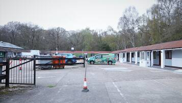 A motel with a parking area, a green van, and a gated entrance.