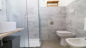 Ein modernes Badezimmer mit Duschkabine, Toilette, Bidet und Waschbecken.