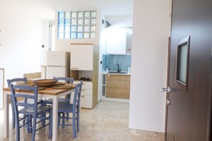 A compact kitchen with a dining table, chairs, a refrigerator, and a sink.