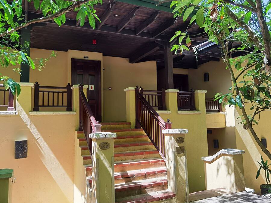 A multi-level building with a staircase, wooden railings, and a door.
