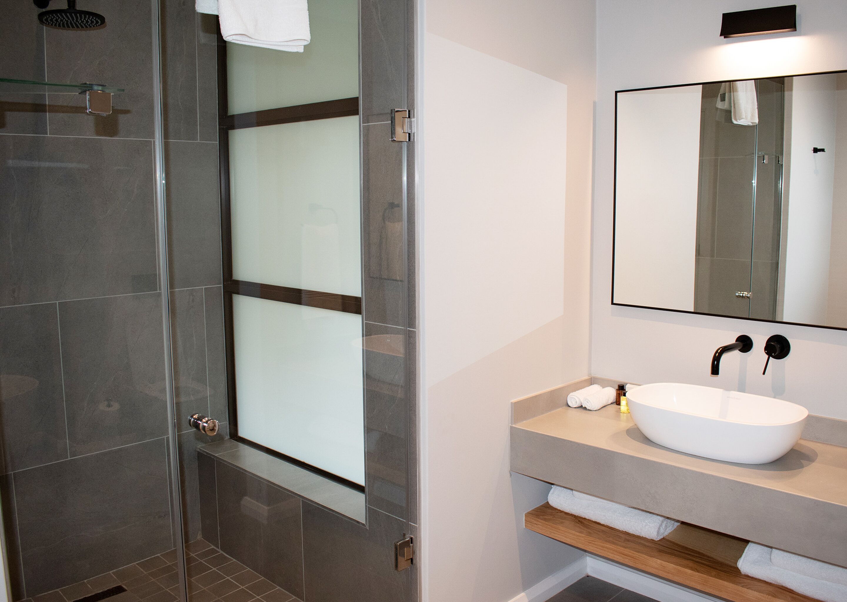 Un baño moderno con cabina de ducha de vidrio, un lavabo blanco y un espejo encima.