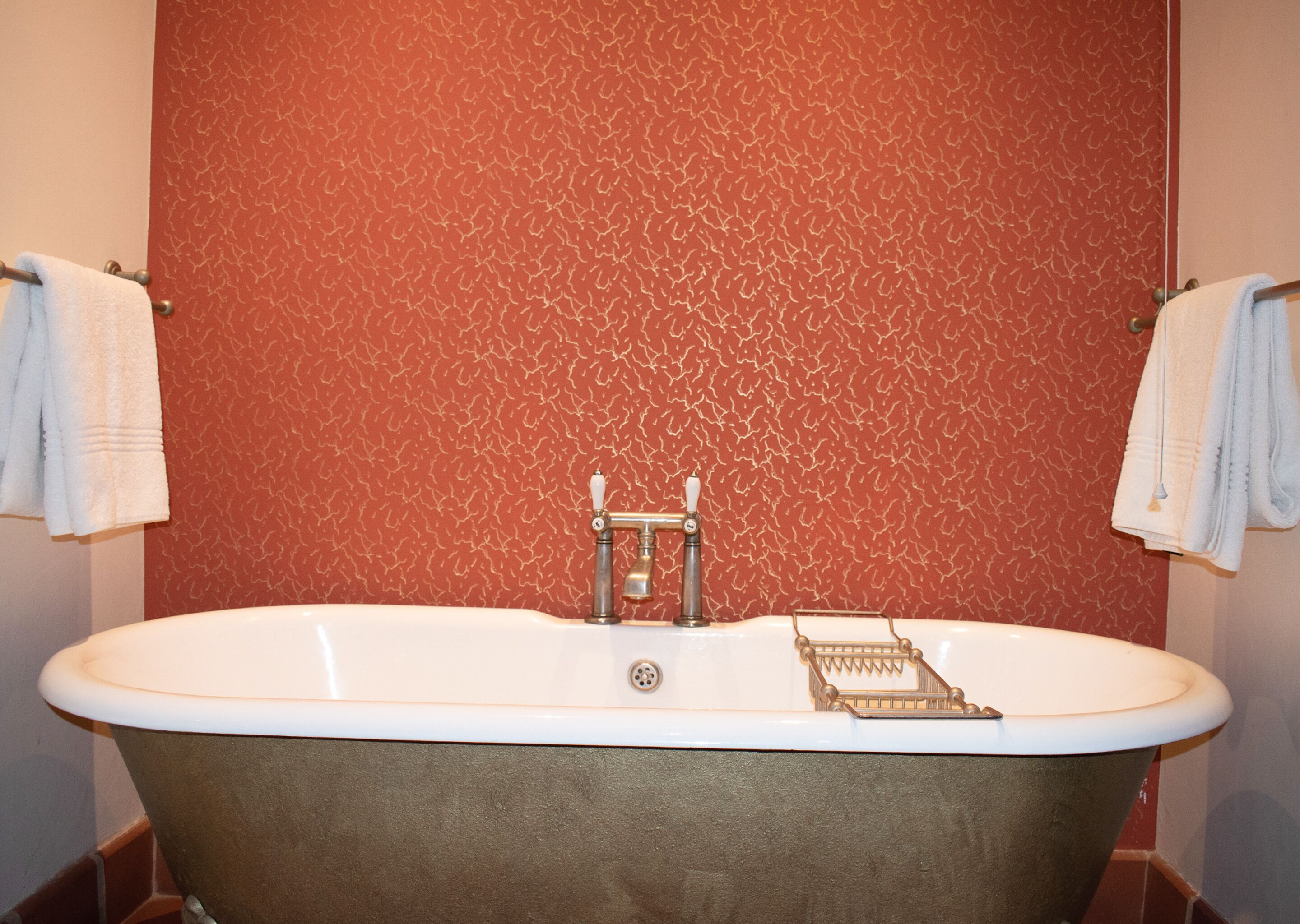 Ein Badezimmer mit freistehender Badewanne, einem Handtuchhalter und einer Wand mit Muster.