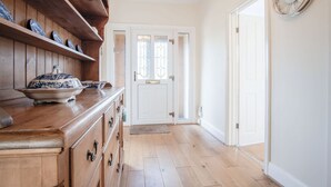 A hallway with wooden flooring, a white door with glass panels, and a wall-mounted clock. - Sorrento - 3 Bed Holiday Home - Wisemans Bridge (Narberth)