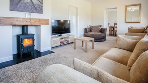 A cozy living room with a fireplace, a television, and comfortable seating. - Sorrento - 3 Bed Holiday Home - Wisemans Bridge (Narberth)