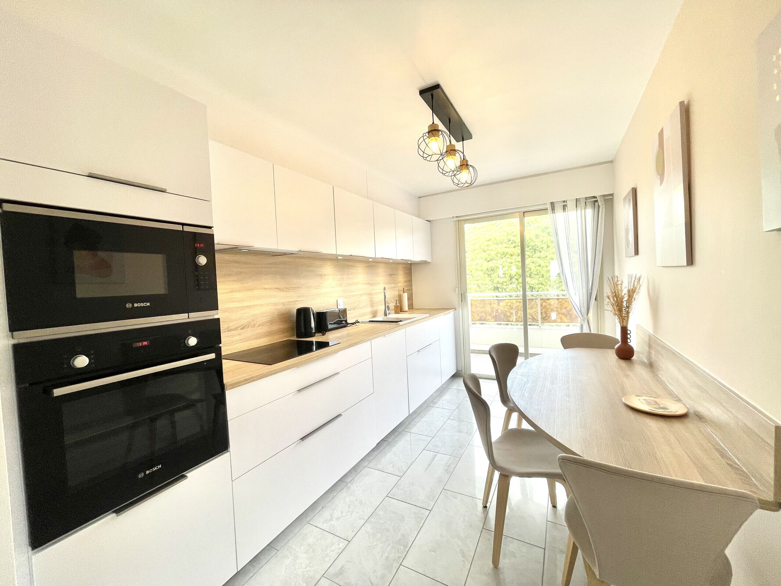 Een moderne keuken met een Bosch oven, een houten aanrechtblad en een eethoek met een tafel en stoelen.
