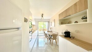 A modern kitchen with a dining area, a wooden shelf, and a view to the outside. - Vezelay 3 (Cannes)
