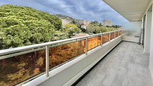 A balcony with a glass railing overlooking a cityscape with trees and buildings. - Vezelay 3 (Cannes)