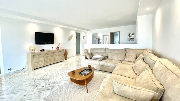 A modern living room with a sofa, a coffee table, and a TV mounted on the wall. - Vezelay 3 (Cannes)