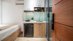 Cocina compacta con lavavajillas integrado, microondas y cafetera sobre una encimera blanca.