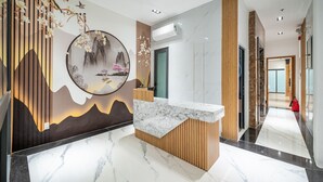 Una zona de recepción moderna con una encimera de mármol, detalles de madera y una pared decorativa con una escena natural.