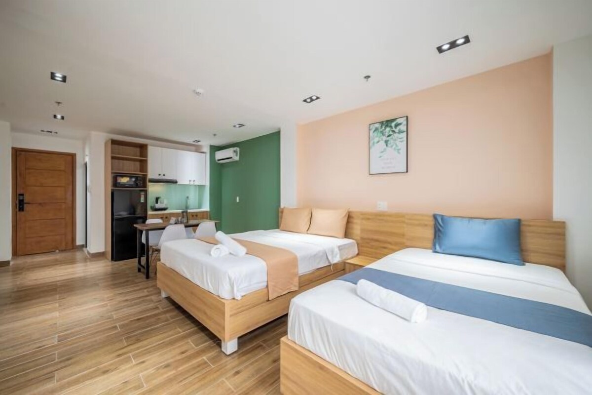 A hotel room with two beds, a kitchenette, and a dining area.