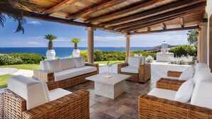 Un patio al aire libre con mobiliario de mimbre y vistas al océano.