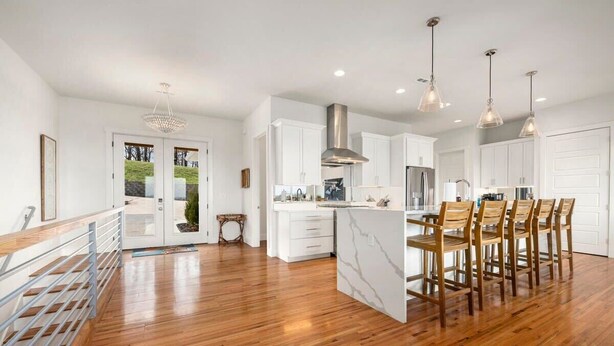 A spacious kitchen with white cabinetry, a central island with chairs, and pendant lighting.