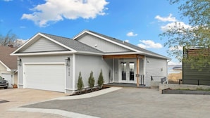 A single-story house with a garage, a covered porch, and a landscaped driveway.