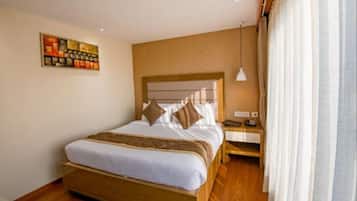 A hotel room with a large bed, a nightstand, a lamp, and a painting on the wall.