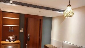 A modern hotel room with a wooden wardrobe, a sofa, a coffee table, and a hanging light fixture. - Yashshree Imperial  (Siliguri)