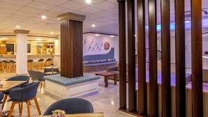 Un moderno vestíbulo de hotel con una zona de estar, un bar y una pared decorativa con un mural de aves.