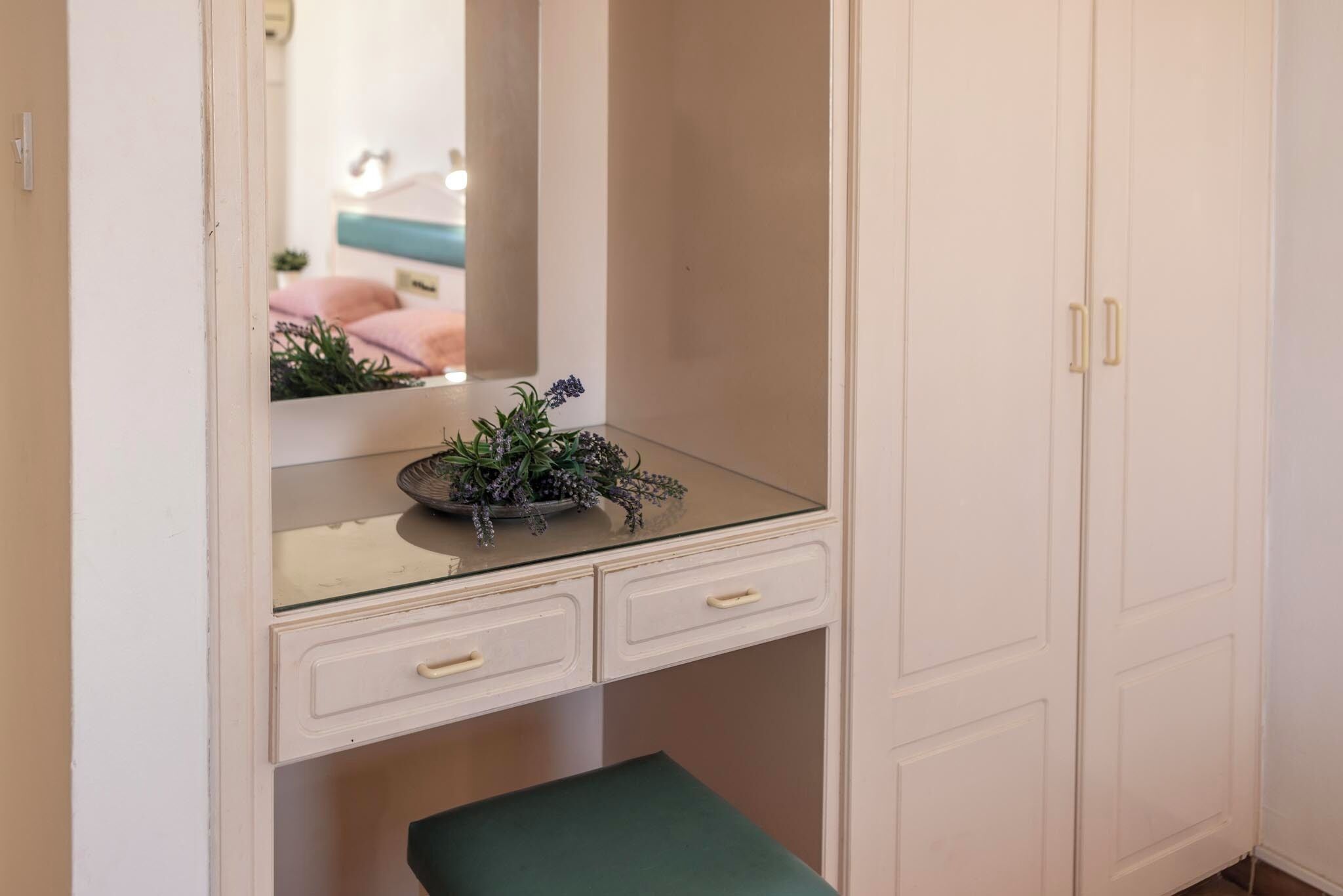 Un piccolo e compatto specchio da trucco bianco con piano in vetro, due cassetti e specchio.