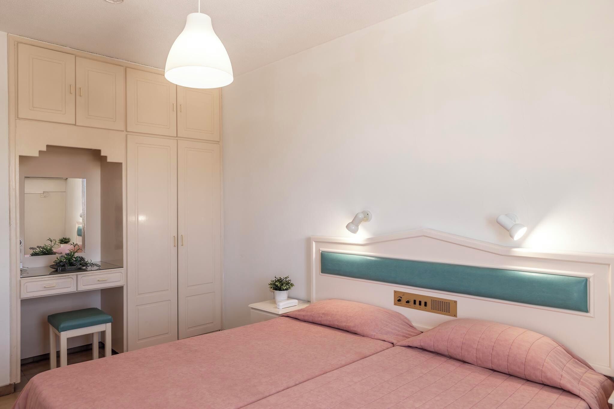 Une chambre à coucher avec un lit, une table de chevet, une commode et un miroir.