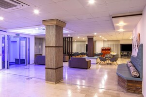 A spacious lobby with a central seating area, a reception desk, and an exit sign.