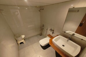 A modern bathroom with a toilet, bidet, sink, and mirror. - Safron Inn (Pune)