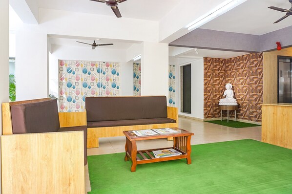 A modern lobby with a sofa, wooden furniture, a green carpet, and patterned walls. - Safron Inn (Pune)