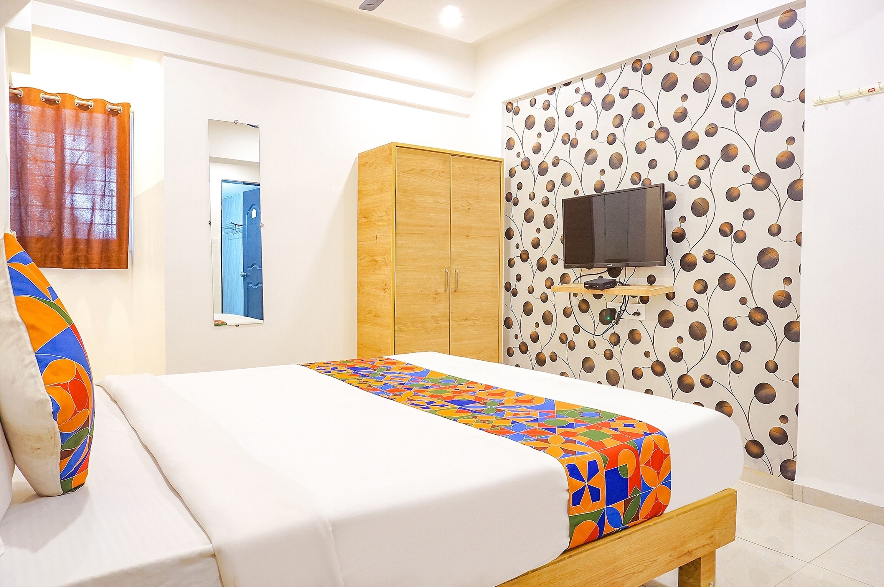 Ein Hotelzimmer mit Bett, Schrank, Fernseher und einer Wand mit Muster.