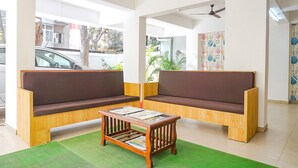 A modern waiting area with wooden sofas, a small wooden table, and a green mat on the floor.