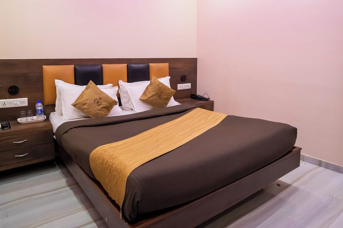 Habitació d'hotel moderna amb un llit gran, un ventilador de sostre i una tauleta de nit amb una ampolla d'aigua i vasos.