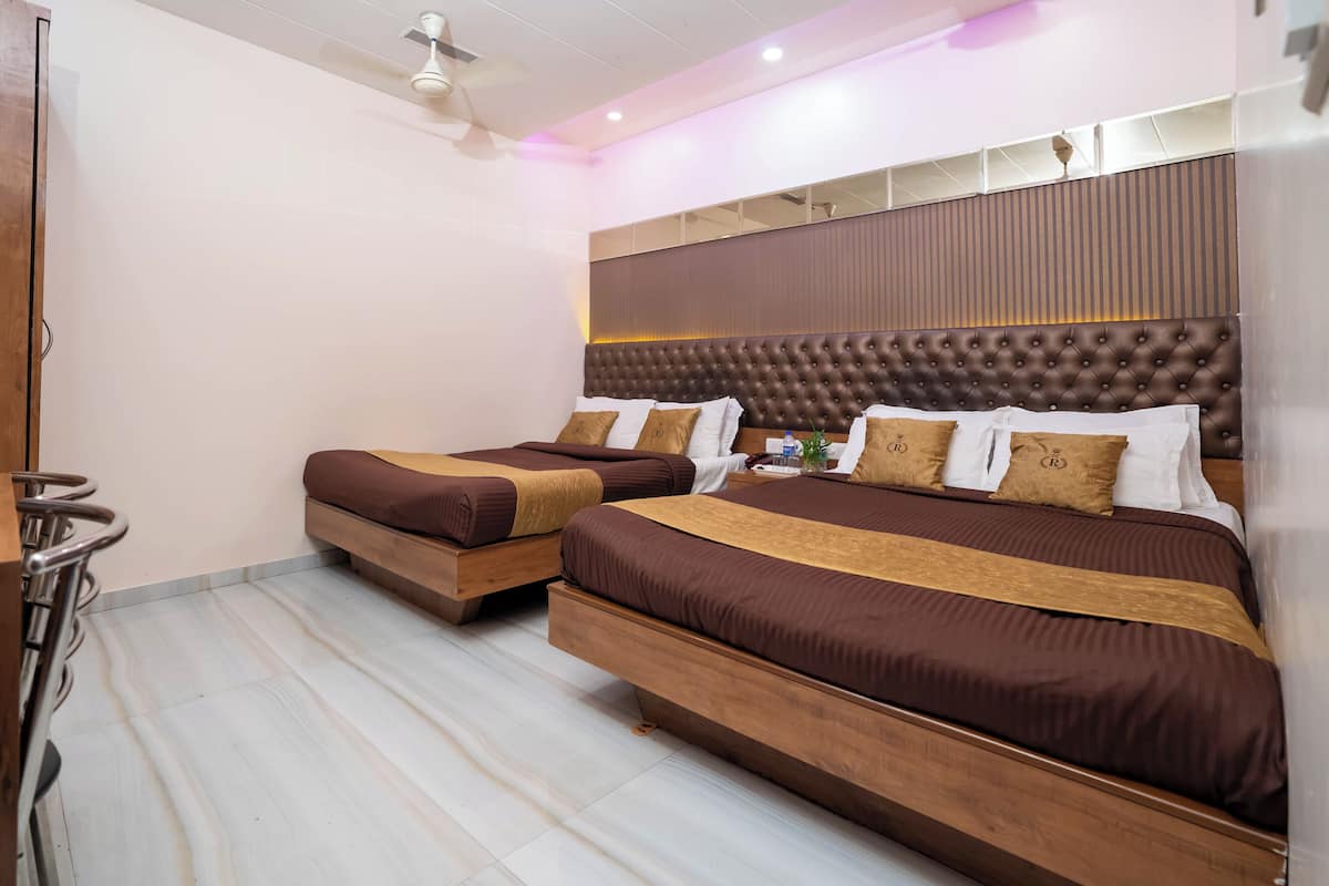 Habitació d'hotel amb dos llits, un panell de capçalera de fusta, un ventilador de sostre i un mirall sobre els llits.