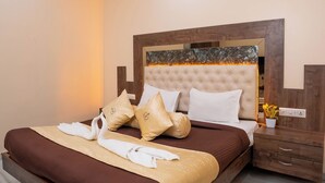 A neatly made bed with a brown bedspread and white pillows, a tufted headboard, and a bedside table with a plant. - Hotel Royce Executive (Mumbai)
