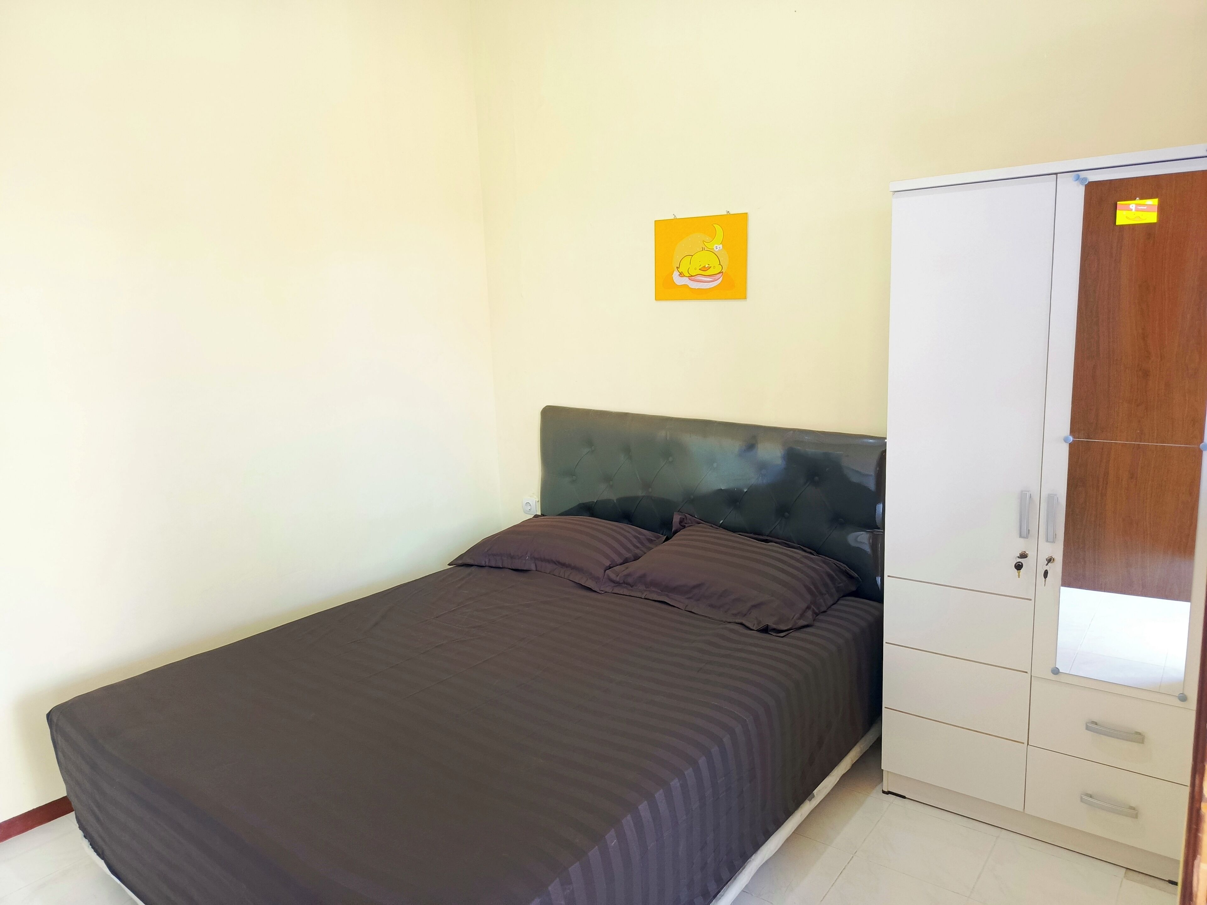 Un dormitorio con cama, armario y un cuadro en la pared.
