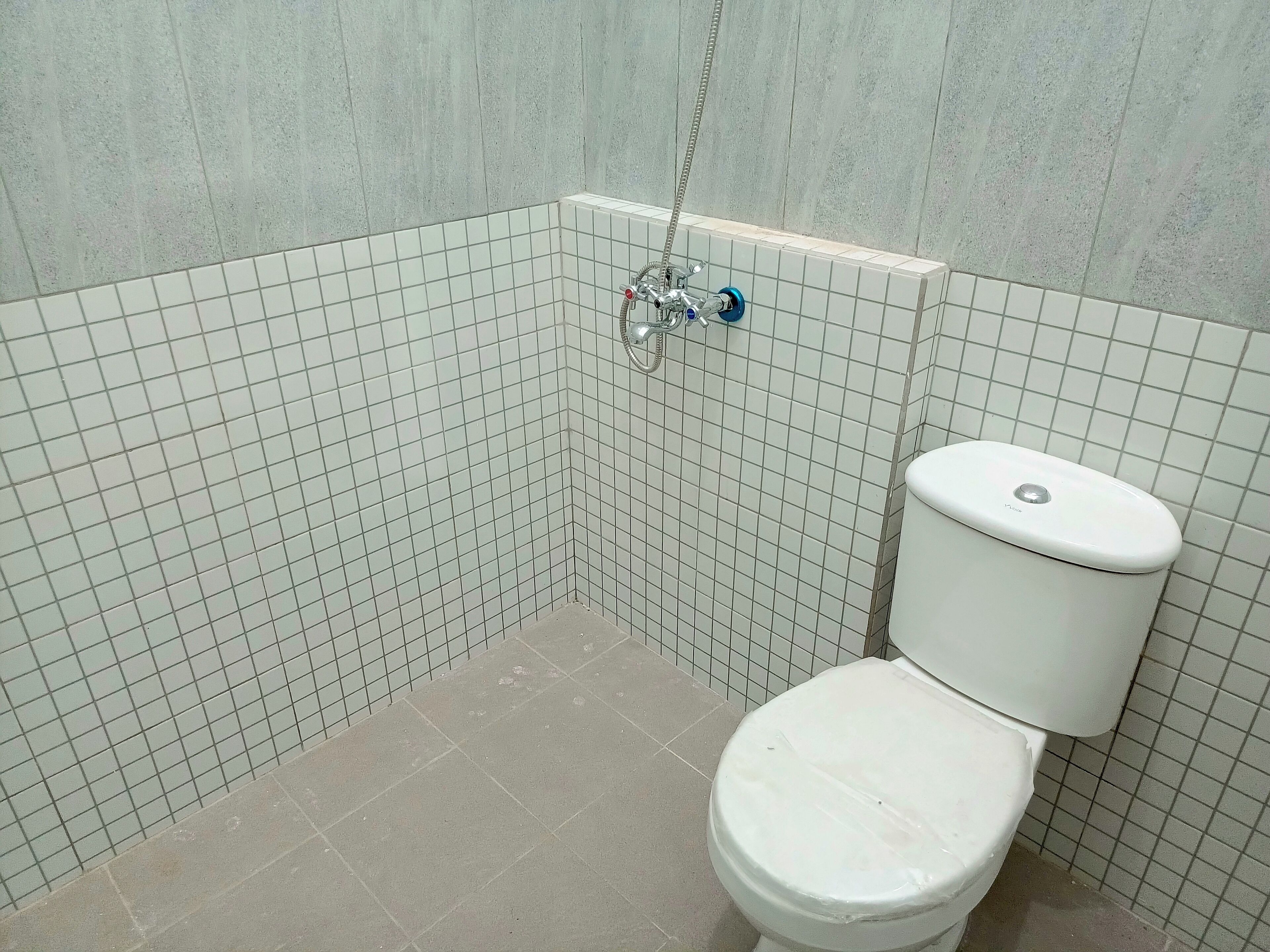 A small, tiled bathroom with a toilet and a shower.