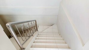 A staircase with a metal handrail and white tiles. - Bebek Kuning Residence (Malang)
