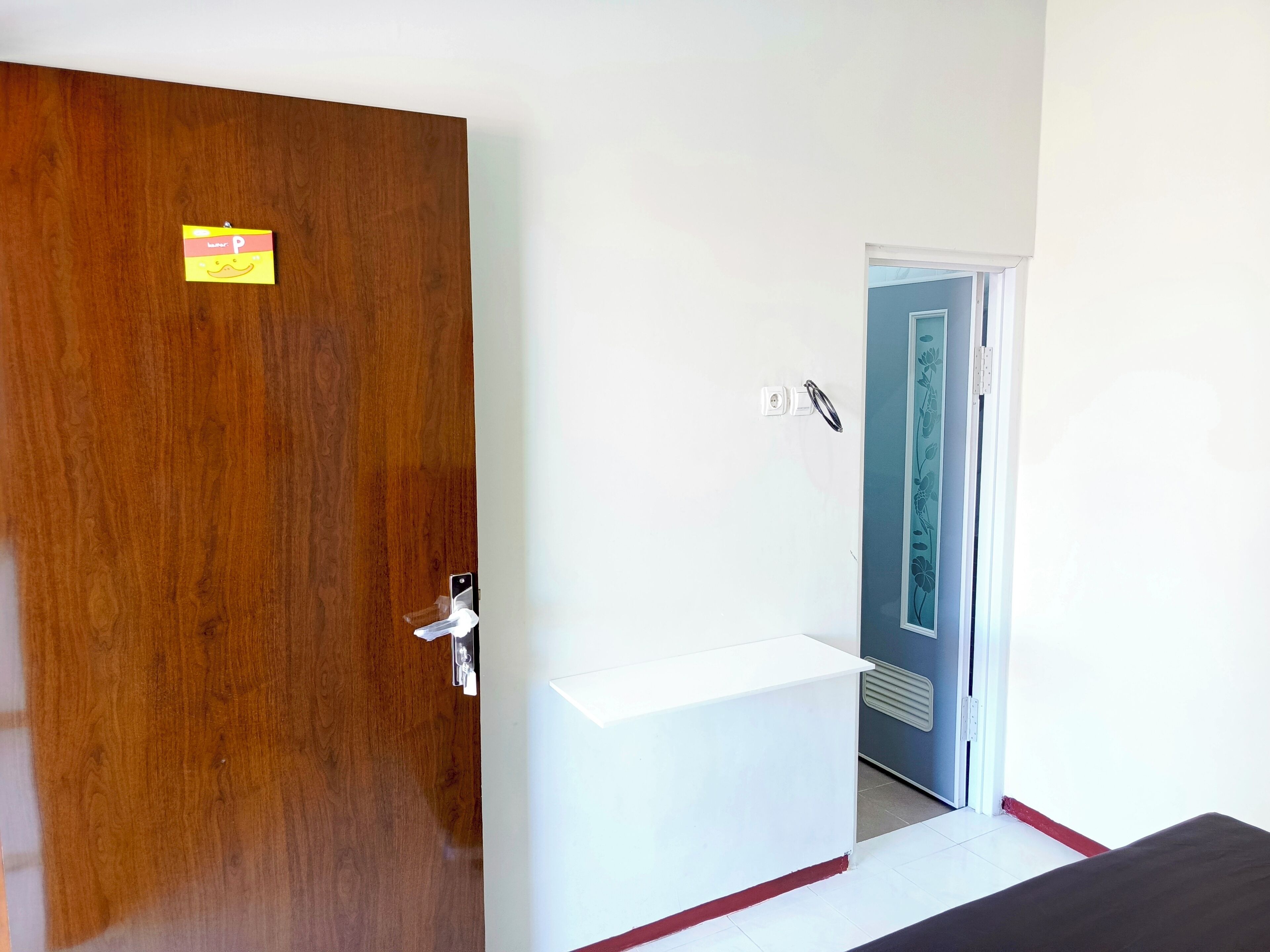 Una habitación con una puerta de madera, una pared blanca y una puerta azul que da a otra habitación.
