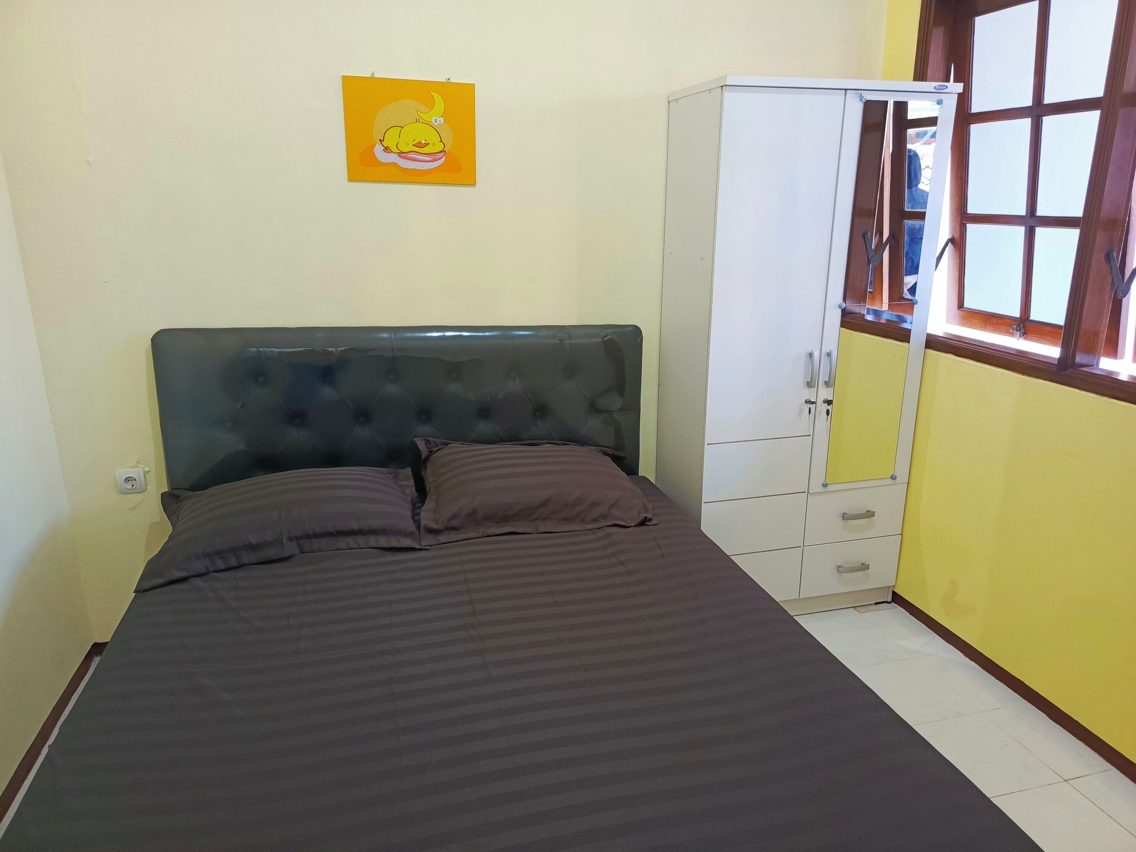 A bedroom with a bed, a wardrobe, a window, and a wall-mounted picture.