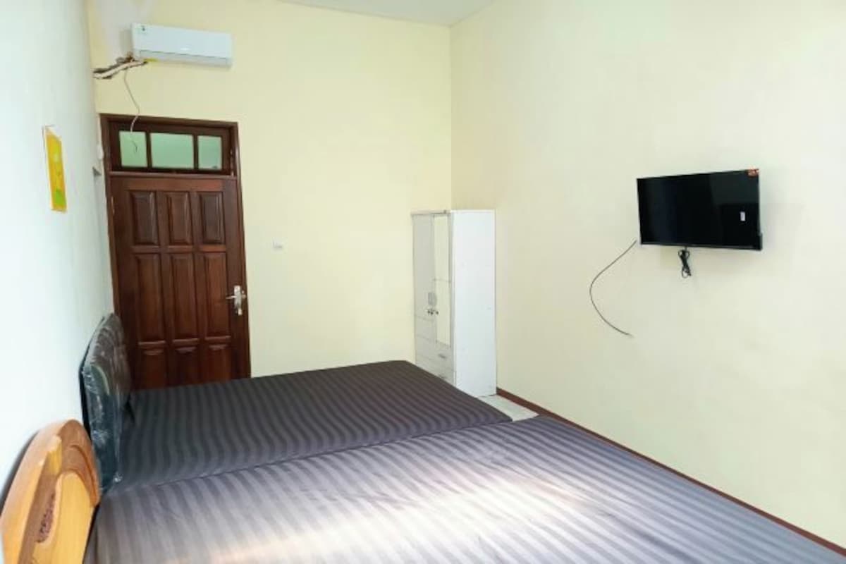 Una stanza con un letto, una TV montata a parete, un armadio e una porta.