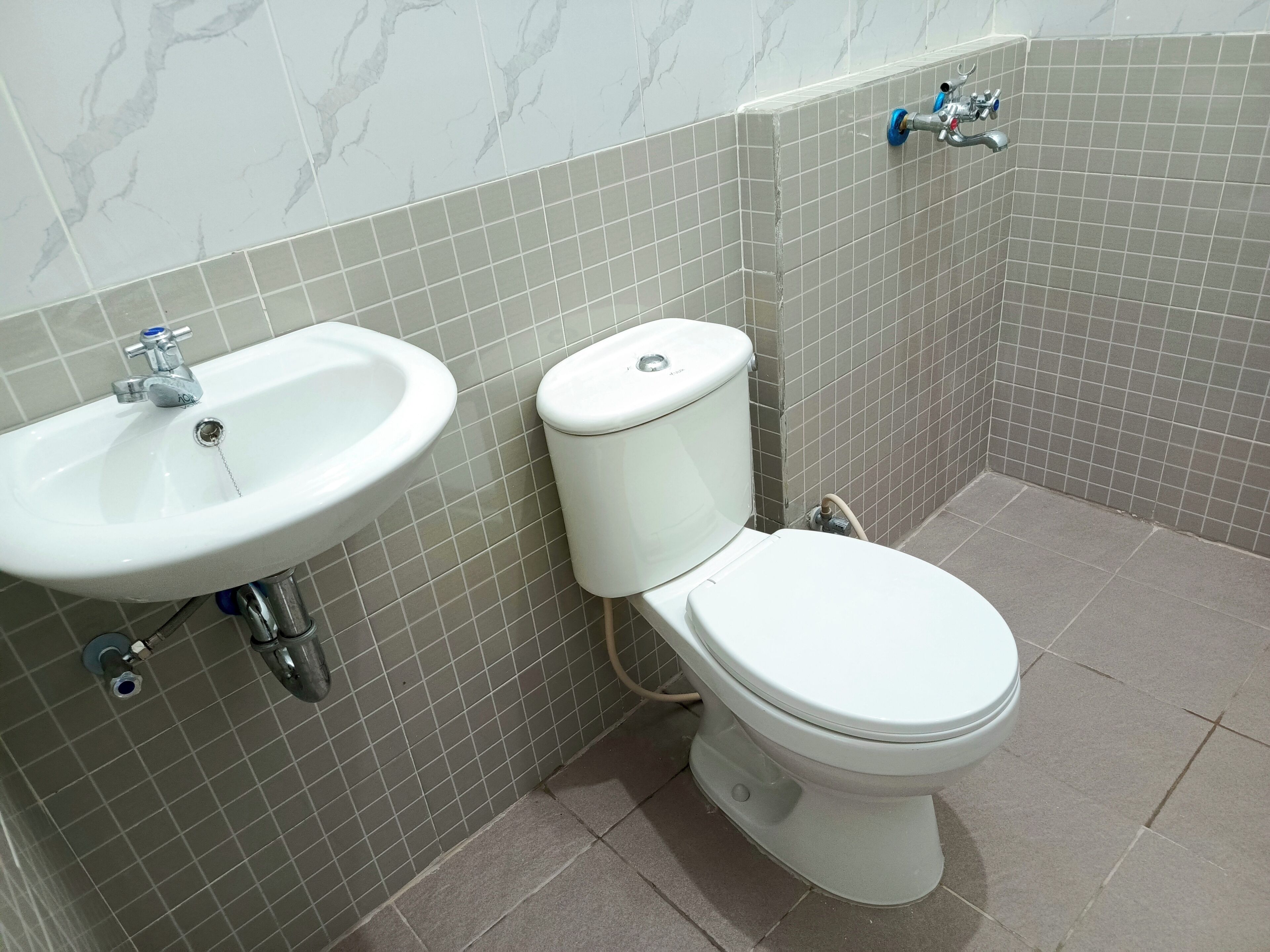 A bathroom with a white sink, toilet, and tiled walls.