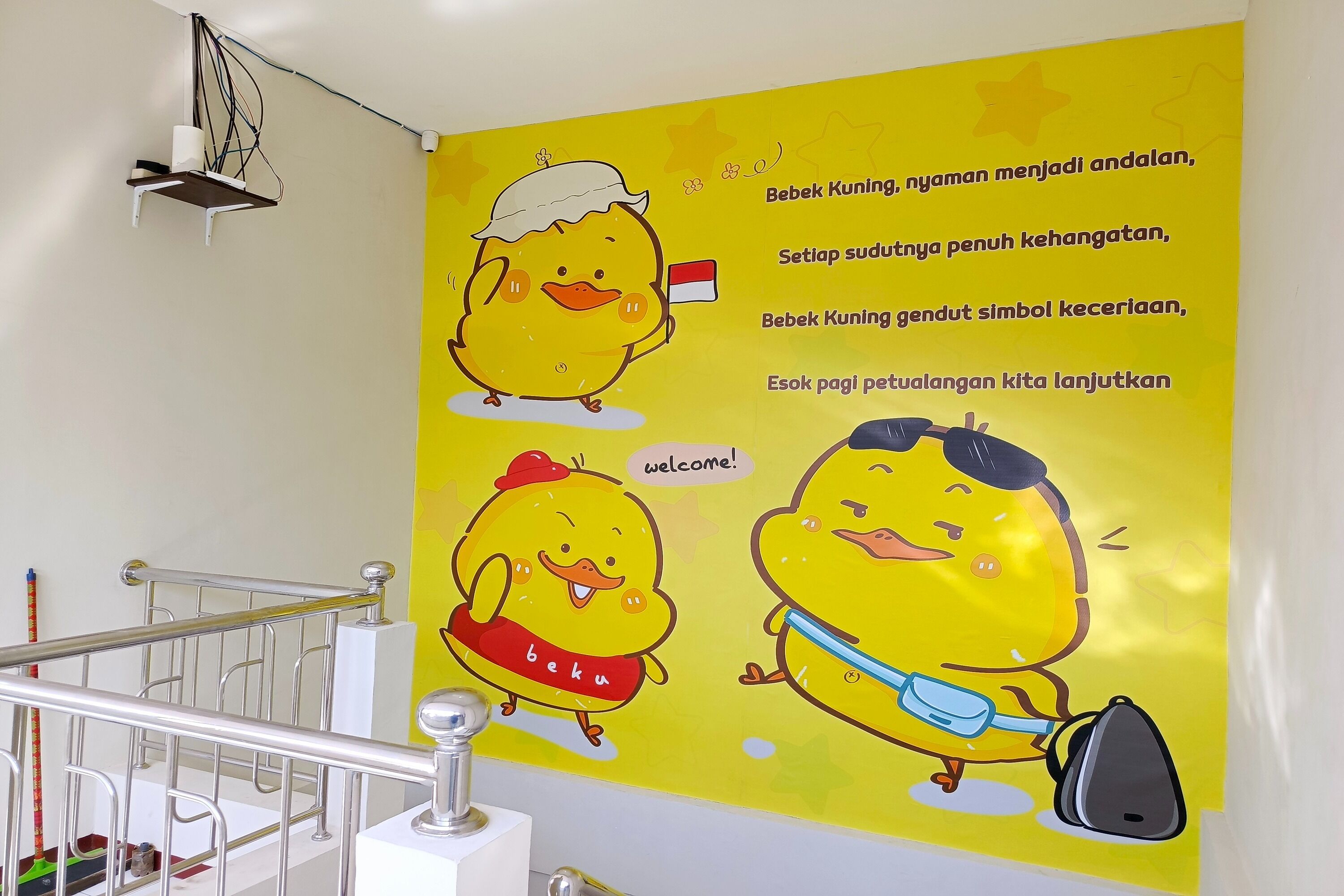 A wall with a yellow poster featuring cartoon ducks and text in a foreign language.