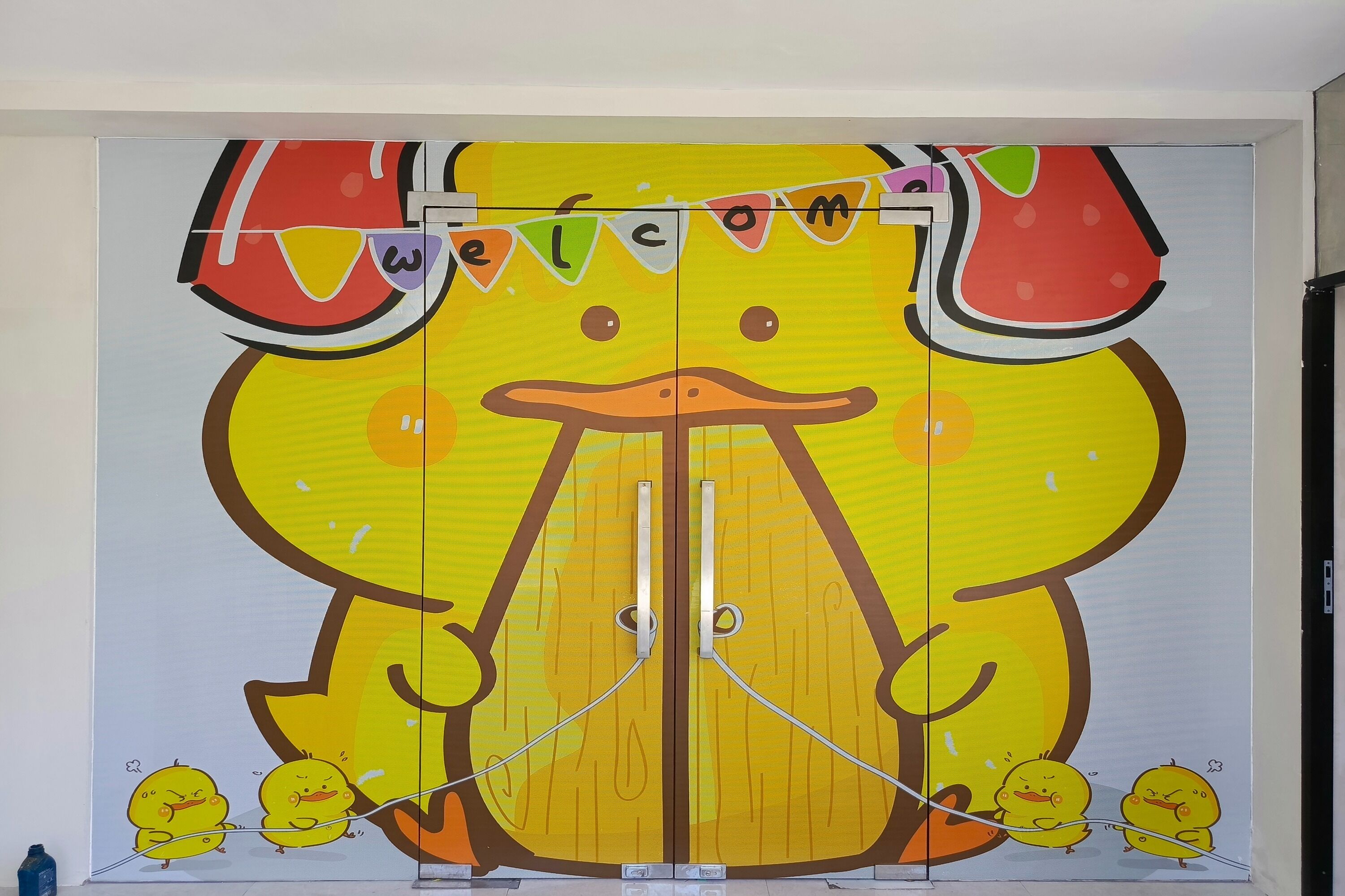 A colorful, cartoon-style door with a 'Welcome' banner and a duck character.