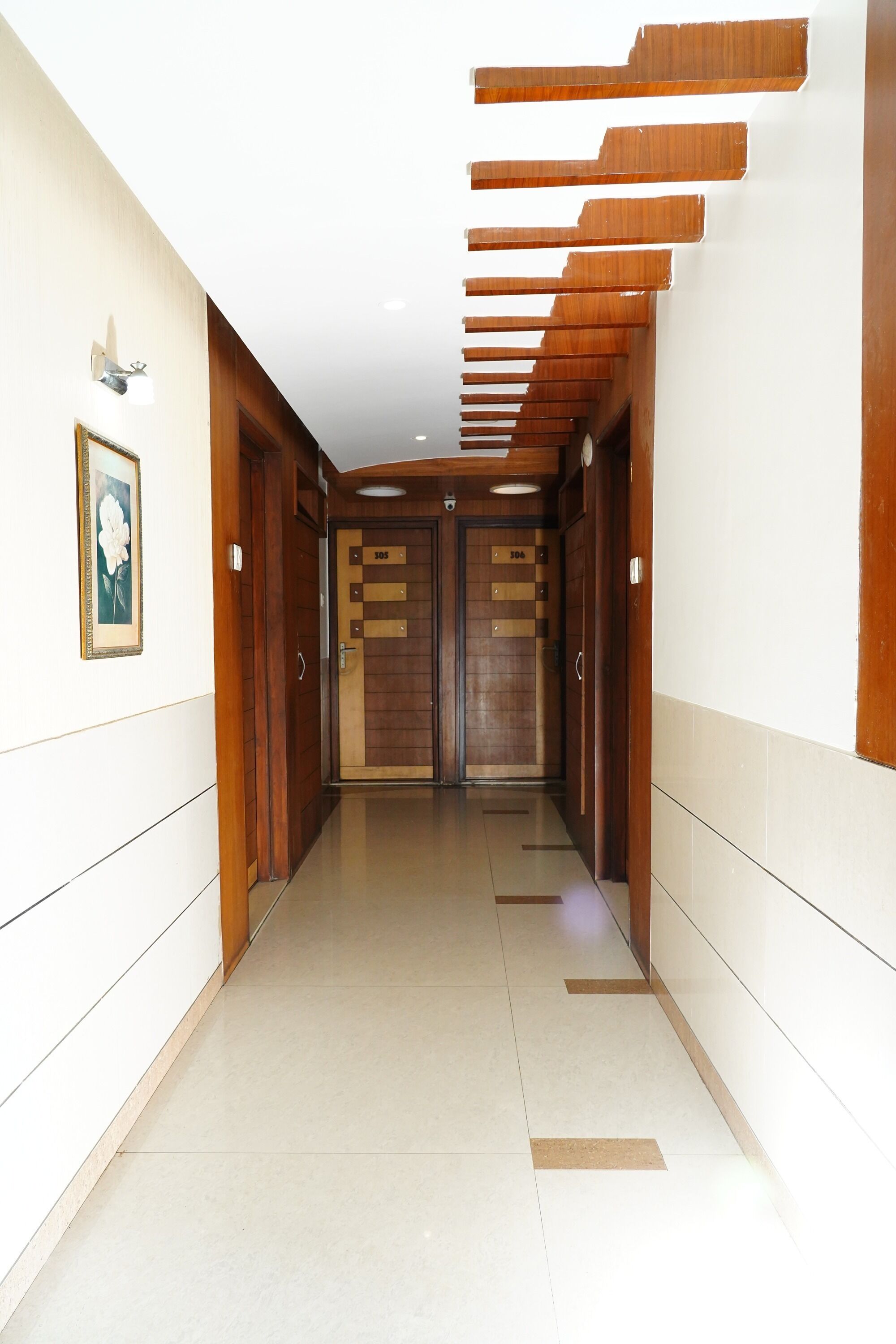 A hallway with wooden doors, a framed picture on the wall, and a light fixture.