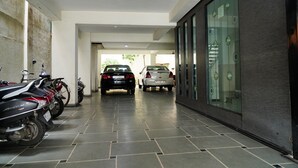 A hallway with parked cars and motorcycles, a tiled floor, and a glass door on the right.